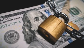 Business safety or financial protection or restriction access. Heap of money in chain with padlock on black. the concept of keeping or banning cash dollars. money is banned.